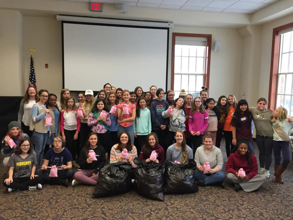 Students and community volunteers holding packed period-care supplies