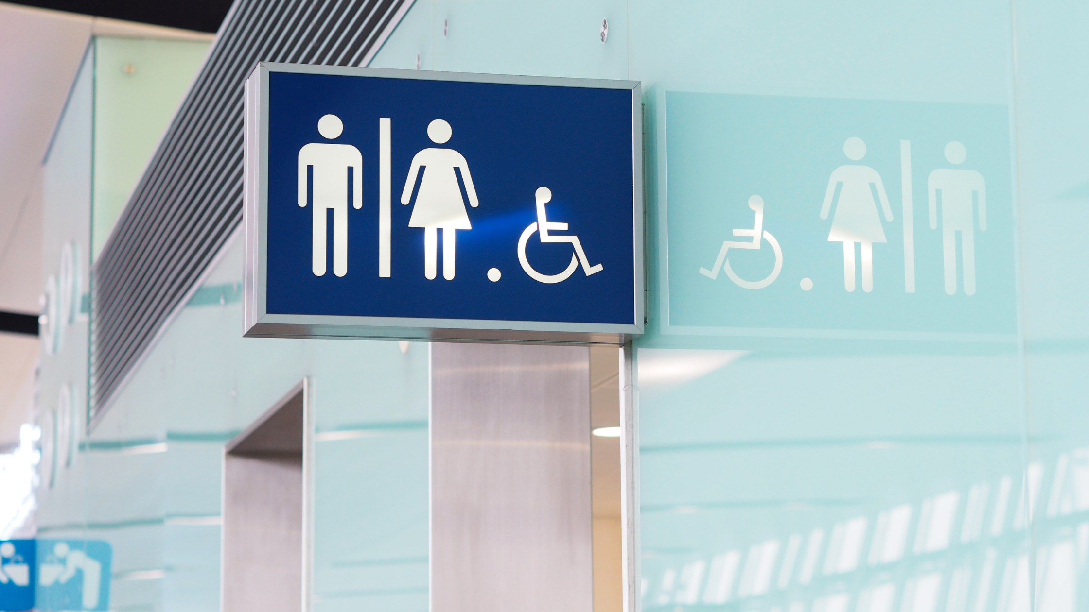 Restroom sign with accessibility icon on a light blue wall.